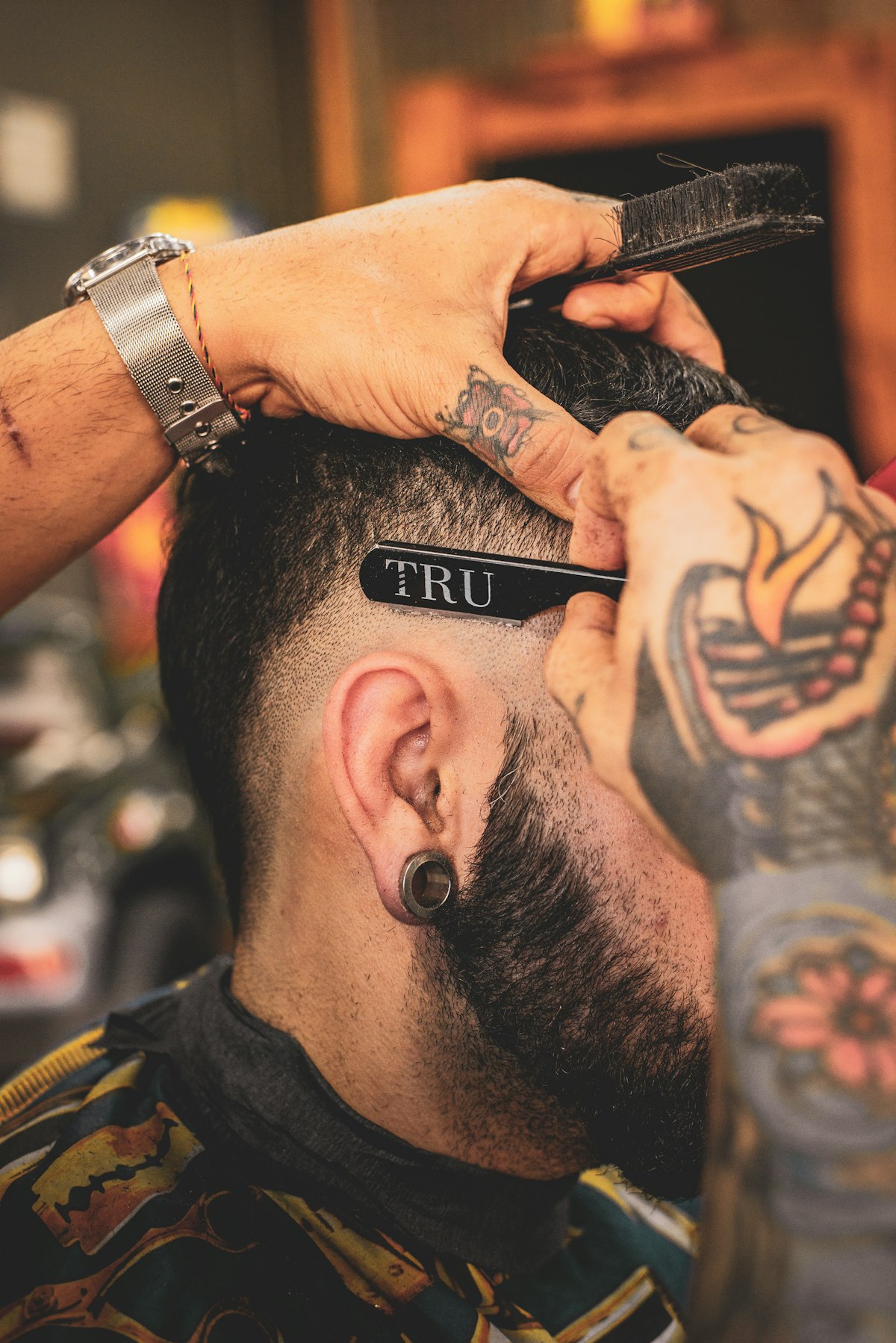 Rafael leaning in with clippers at the back of a fade