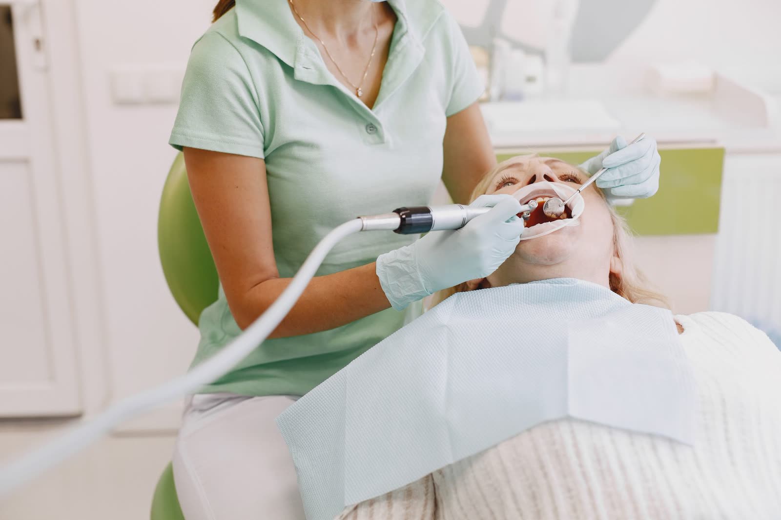 Dental hygienist performing a routine cleaning with digital X-ray equipment nearby