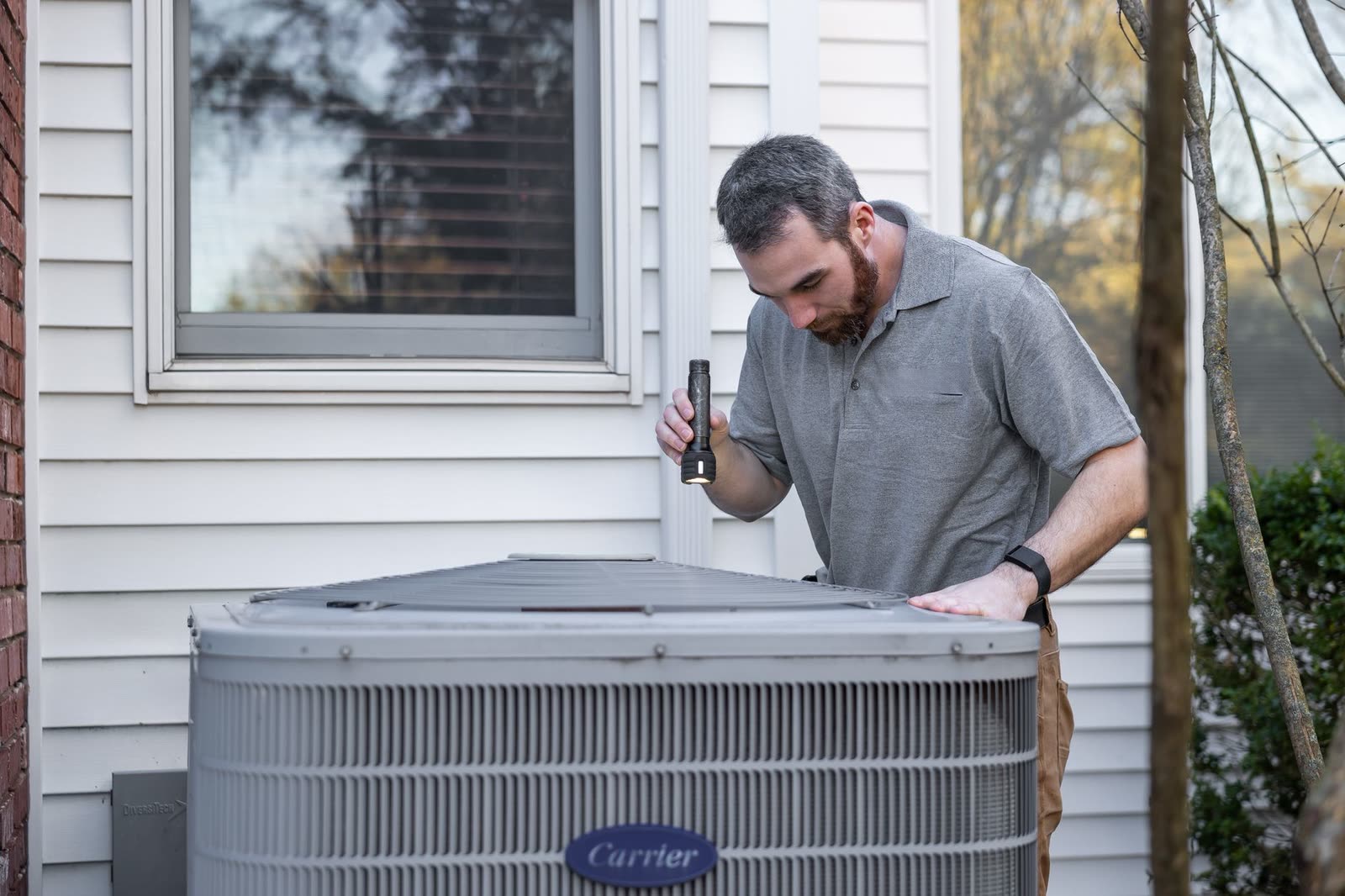 HVAC technician servicing an outdoor air conditioning condenser unit at a Texas home